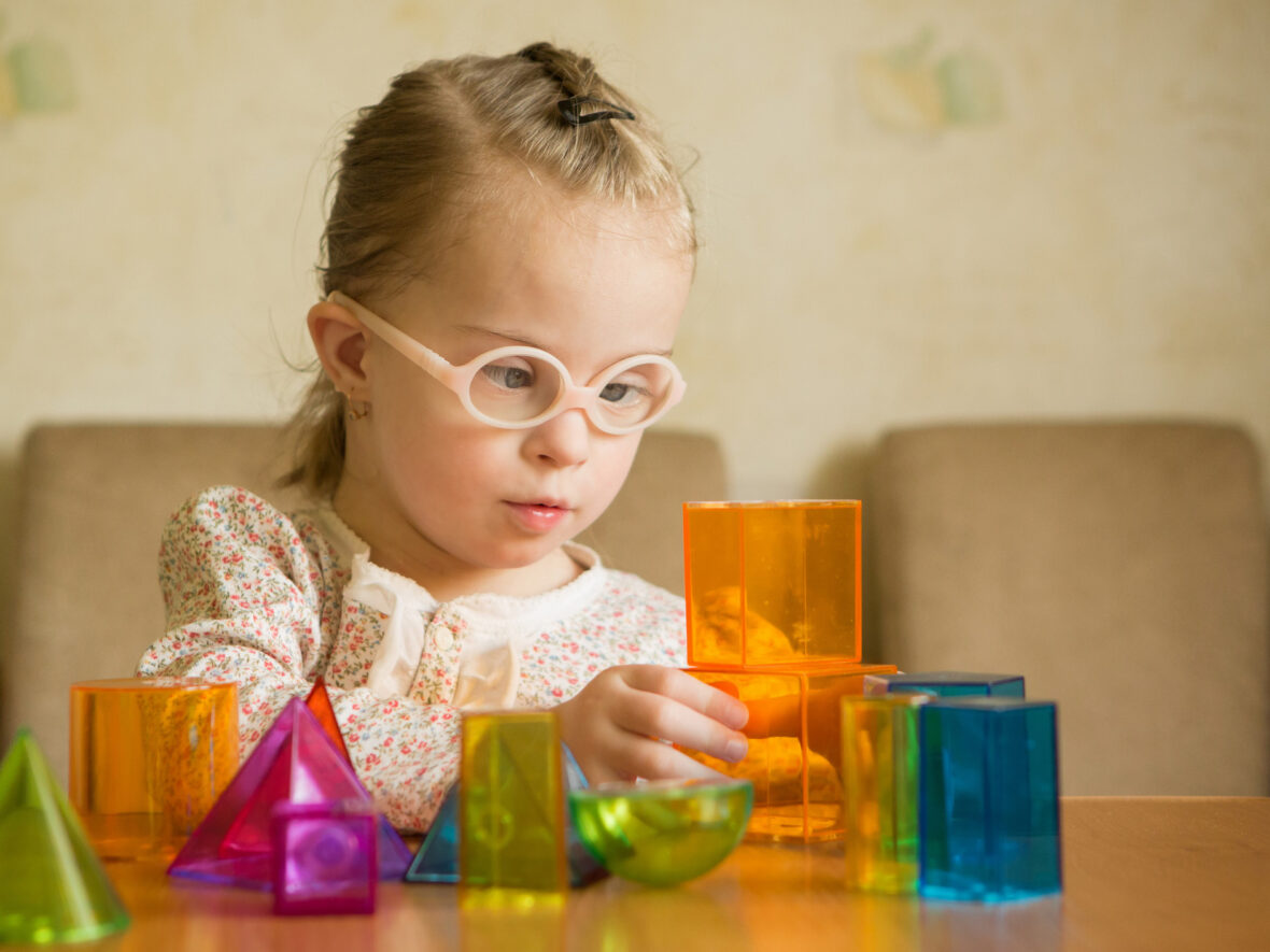 A young female child playing with colourful acrylic blocks