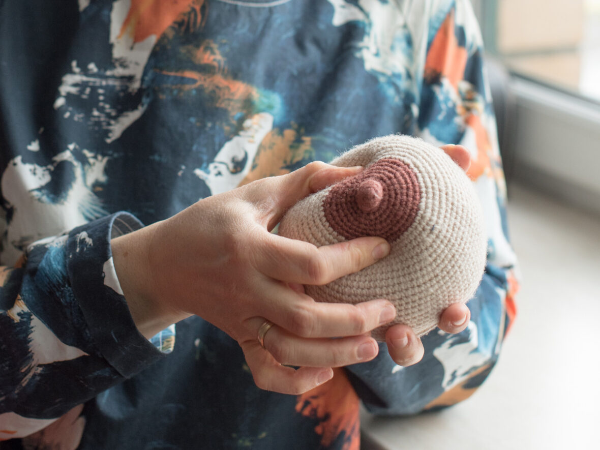 A lactation consultant demonstrating breast feeding techniques on a crochet nipple