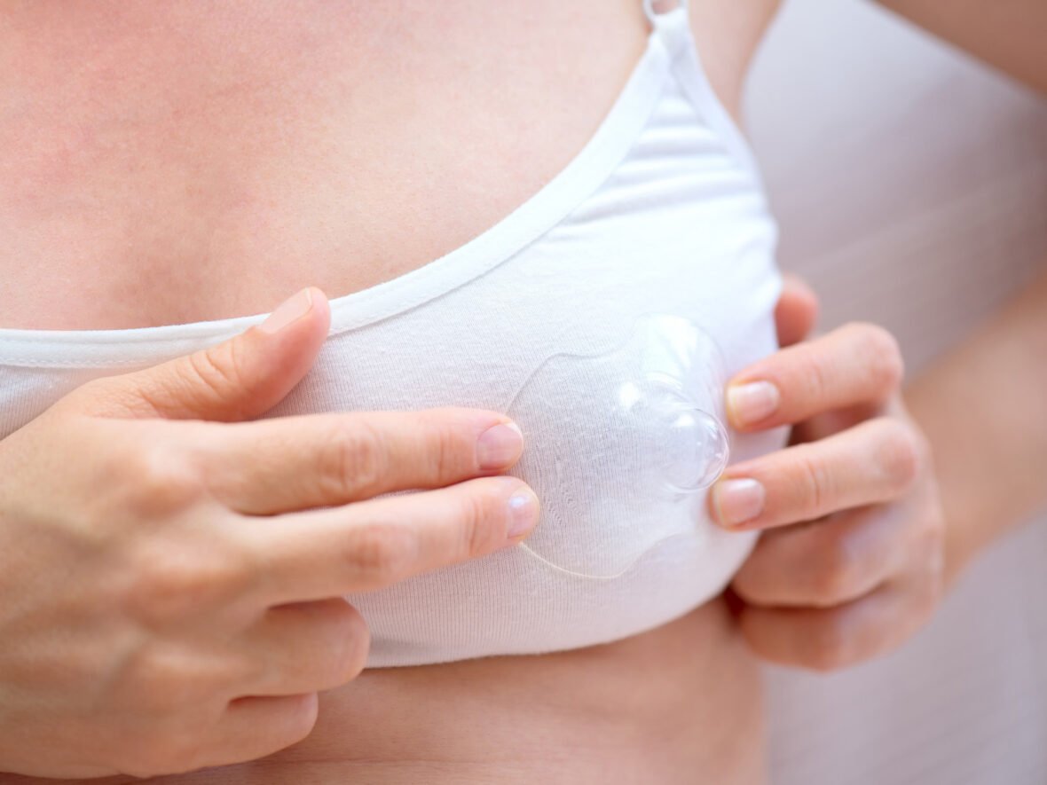 A woman holding a breast shield against her chest to guage appropriate size