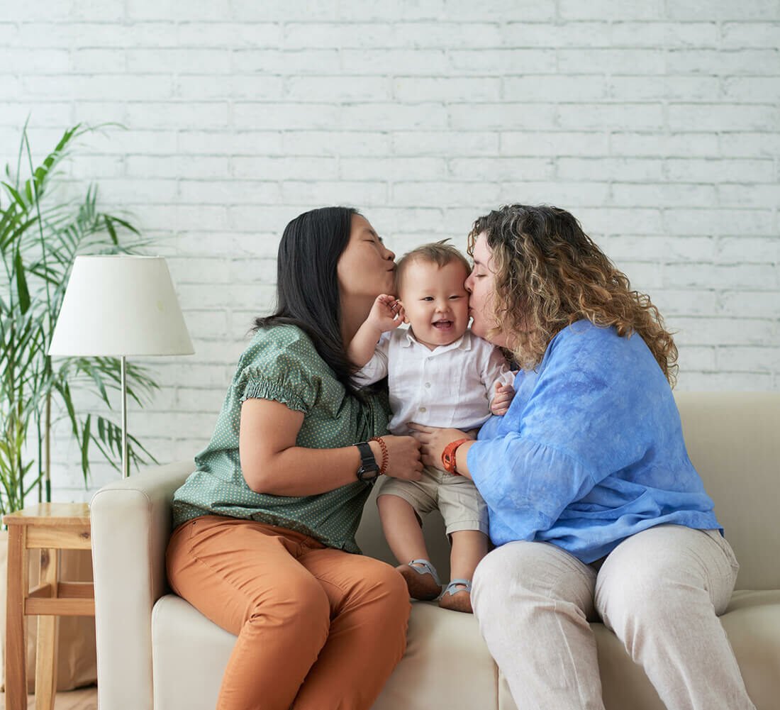 Moms kissing their newborn baby